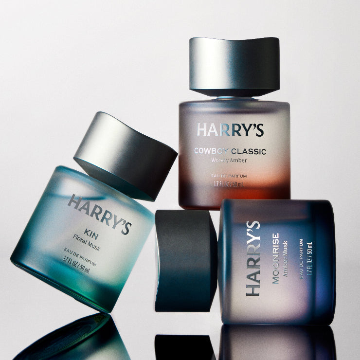 Collection of Harry's skincare and grooming products on a reflective surface with a light gray background.