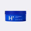 Blue container of H' texturizing putty on a light gray background