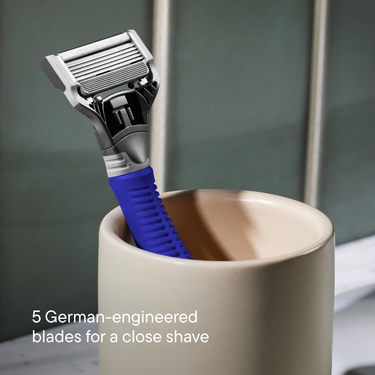 Blue Truman razor resting in an off white ceramic cup.