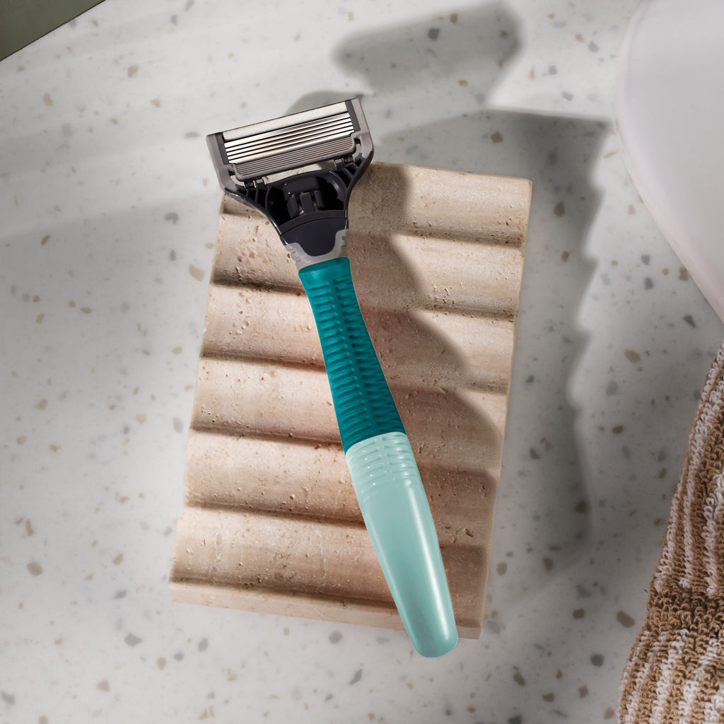 Shaving razor with a green handle on a speckled countertop