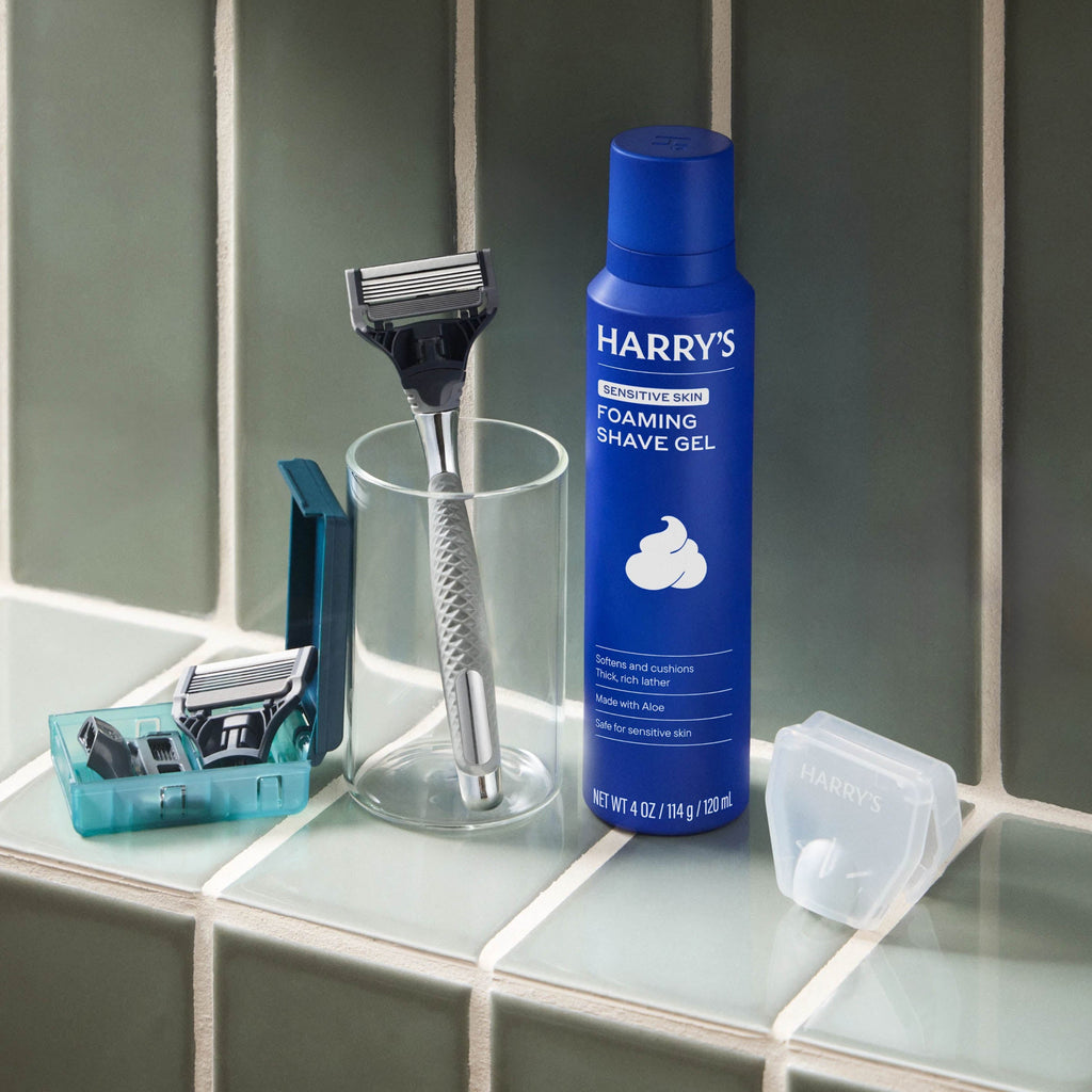 Blue bottle of Harry's shaving gel with a razor and other items on a bathroom counter.