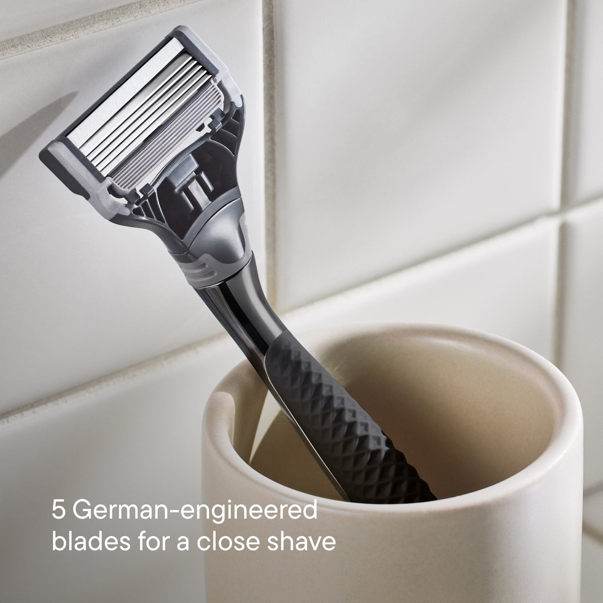 Shaving razor in a white cup with tiled bathroom background